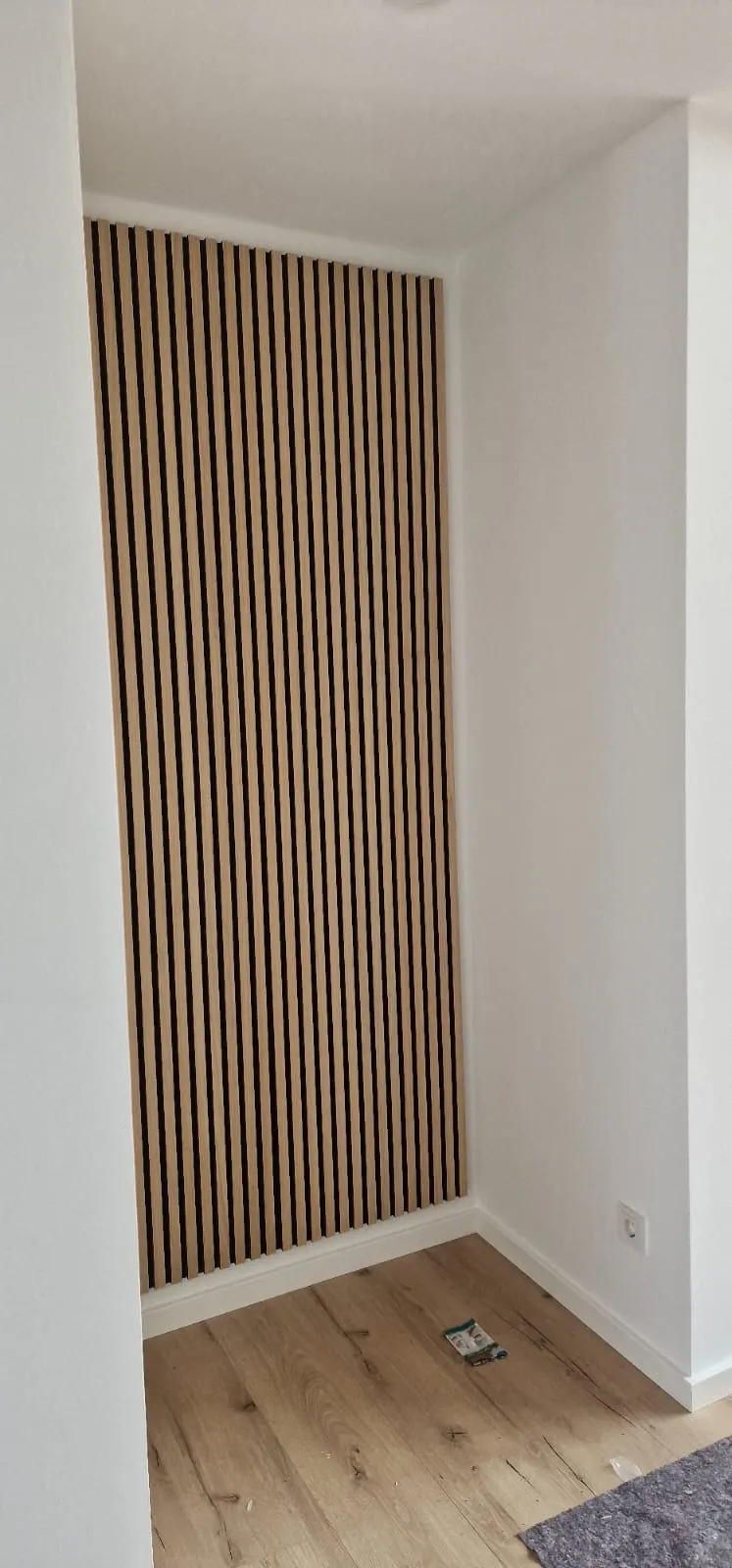 Neu verlegter Holzboden vor einer Wand mit Holzlamellen
