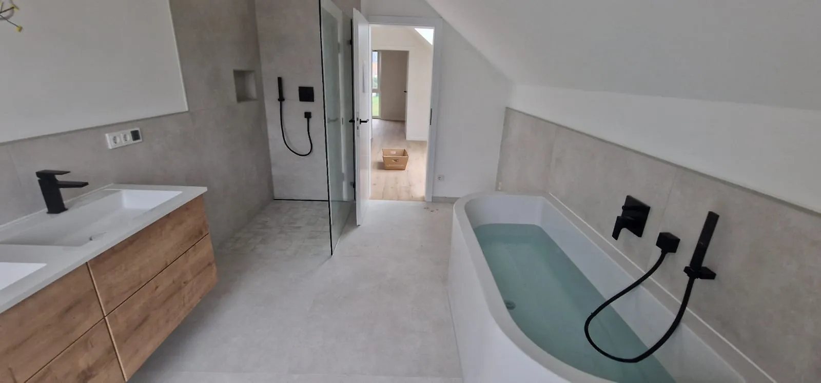 Modernes Badezimmer mit freistehender Badewanne, bodengleicher Dusche und schwarzen Armaturen nach Renovierung durch PC Trockenbau