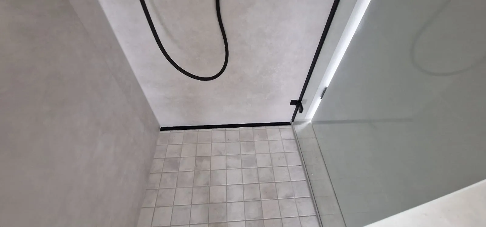 Bodengleiche Dusche mit Glasabtrennung und schwarzen Armaturen