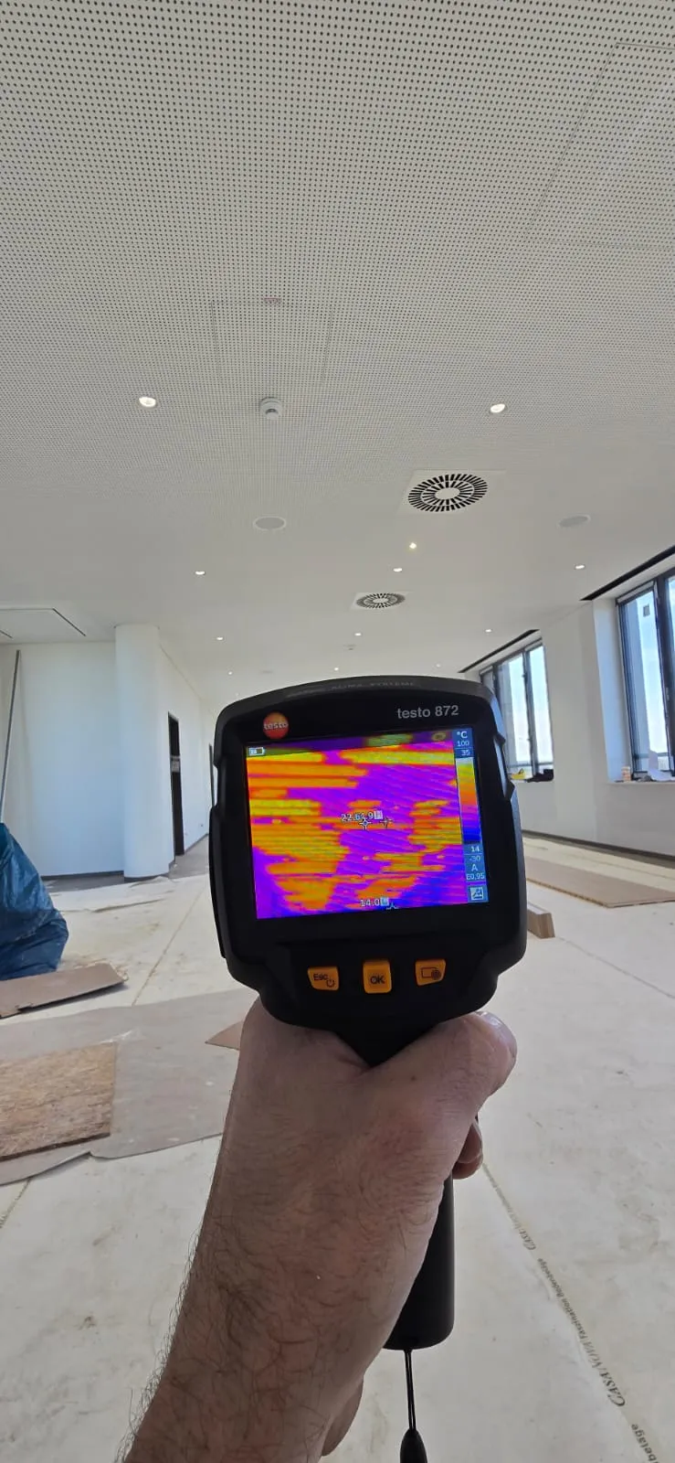 Wärmebildkamera in der Hand vor einer Raumdecke