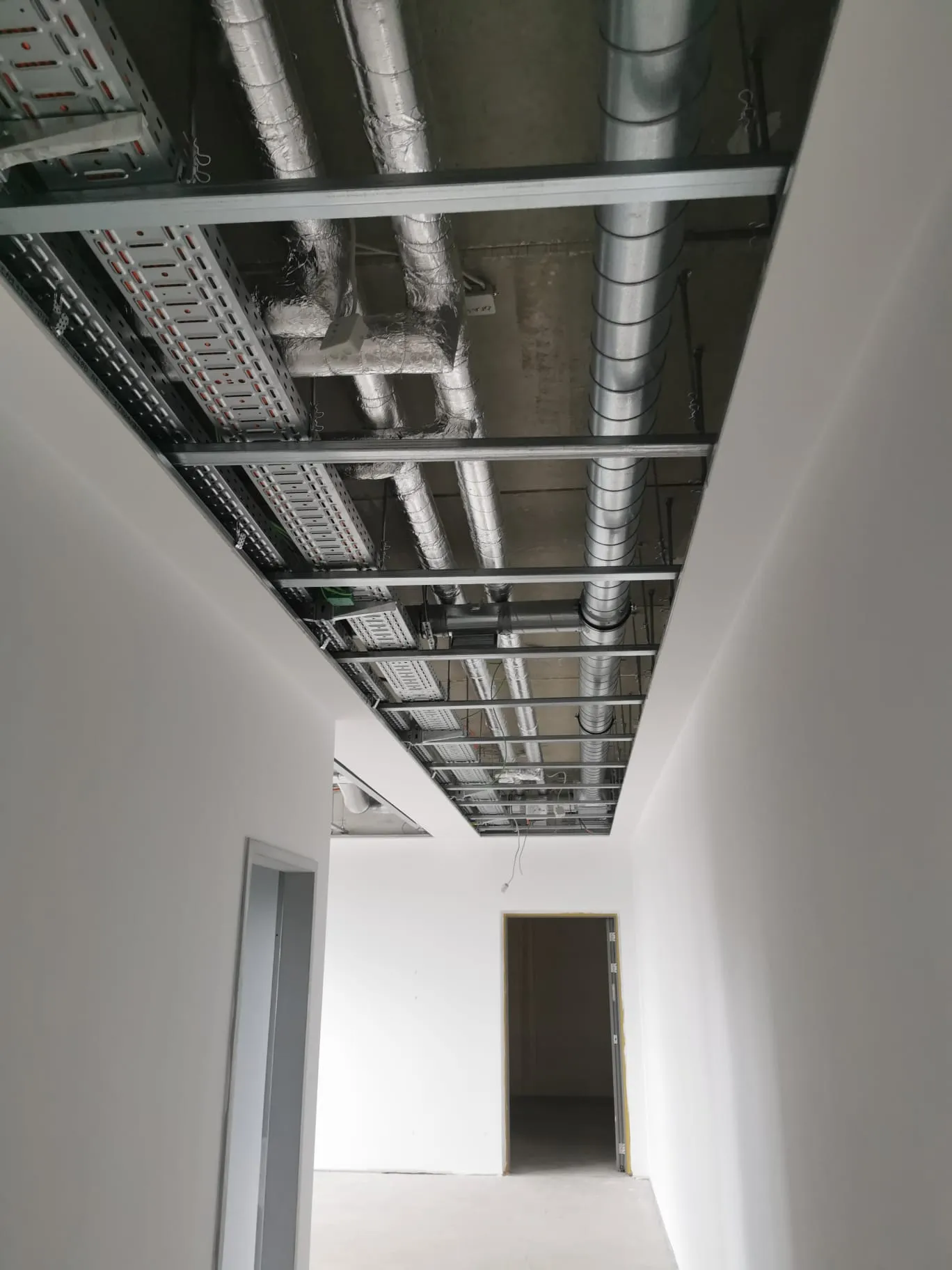 Flur mit offener Decke und sichtbaren Installationen vor der Verkleidung